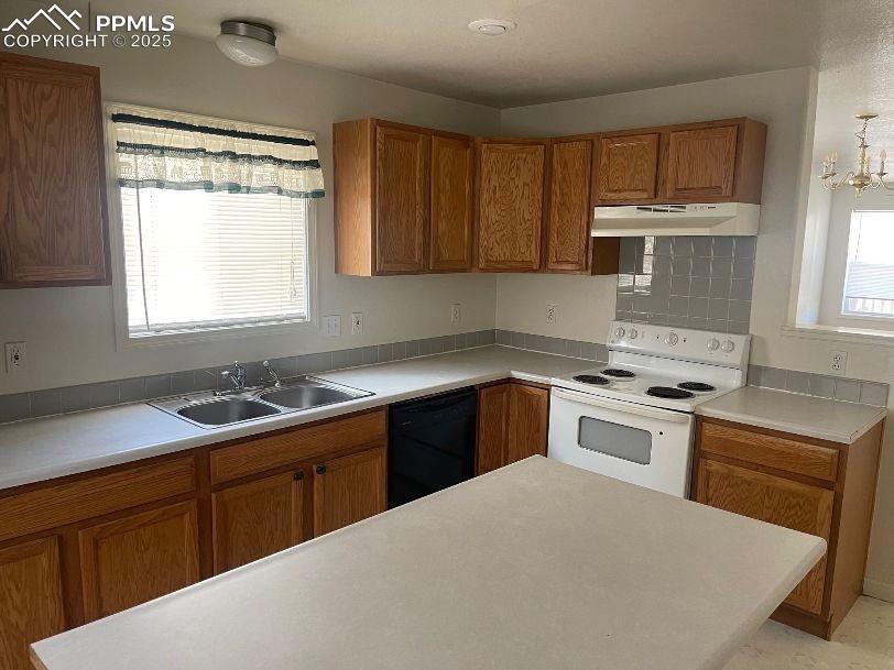 Kitchen with brown cabinets, white range with electric cooktop, and light countertops
