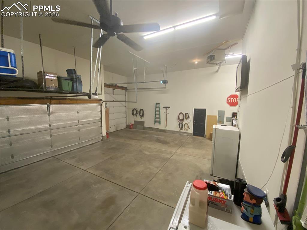 The oversized 4-car heated RV garage includes custom shelving and built-in storage, offering ample parking, workshop space, and organizational convenience for vehicles, tools, and recreational gear