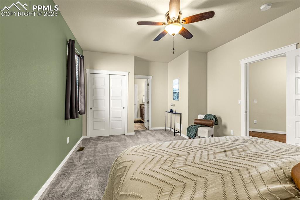 Bedroom with a closet, carpet flooring, a ceiling fan, and ensuite bathroom