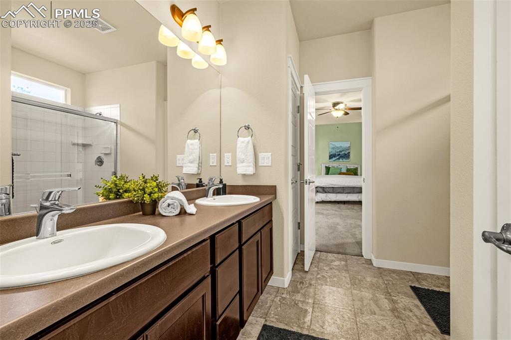 Ensuite bathroom with a stall shower, double vanity, and ceiling fan