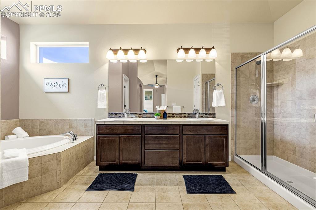 Full bathroom featuring a shower stall, double vanity, a bath, and healthy amount of natural light