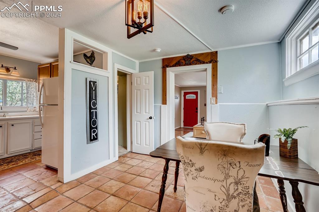 Kitchen featuring white cabinetry, a kitchen breakfast bar, white refrigerator, a textured ceiling, and ornamental molding