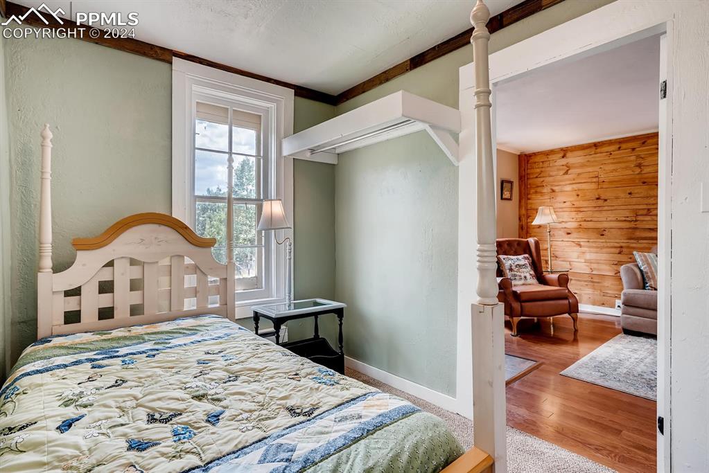 Bedroom featuring hardwood / wood-style flooring, wood walls, and ornamental molding
