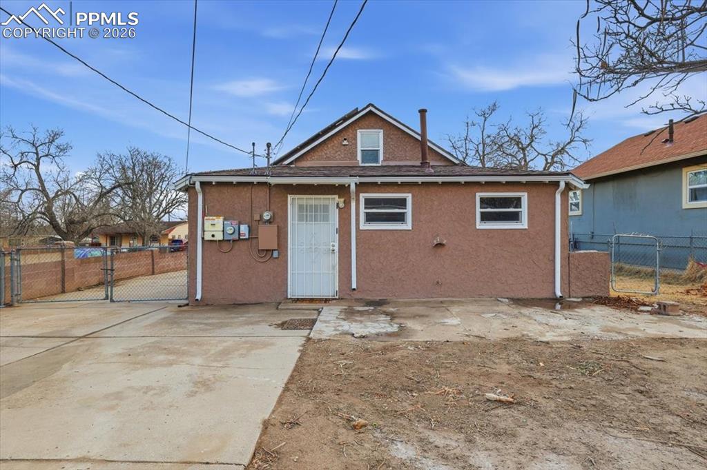 Back of property featuring a gate, stucco siding, and a patio area