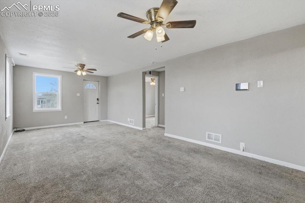 Spare room with carpet flooring, ceiling fan, and a textured ceiling