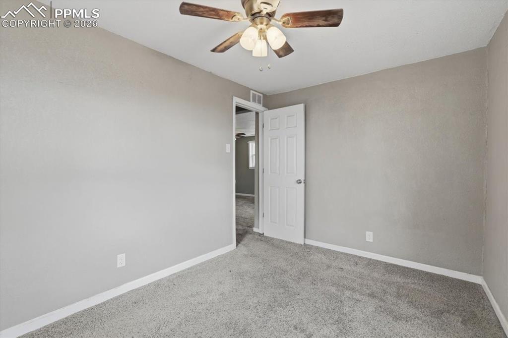 Carpeted spare room featuring baseboards and a ceiling fan