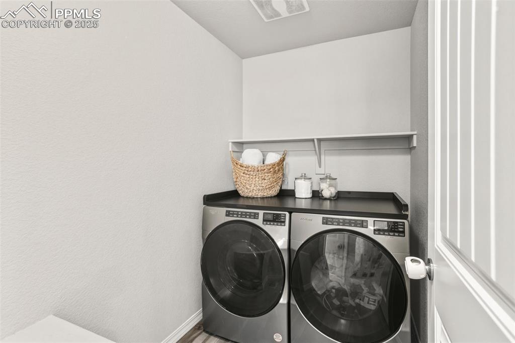 Washroom with washing machine and clothes dryer and a textured wall