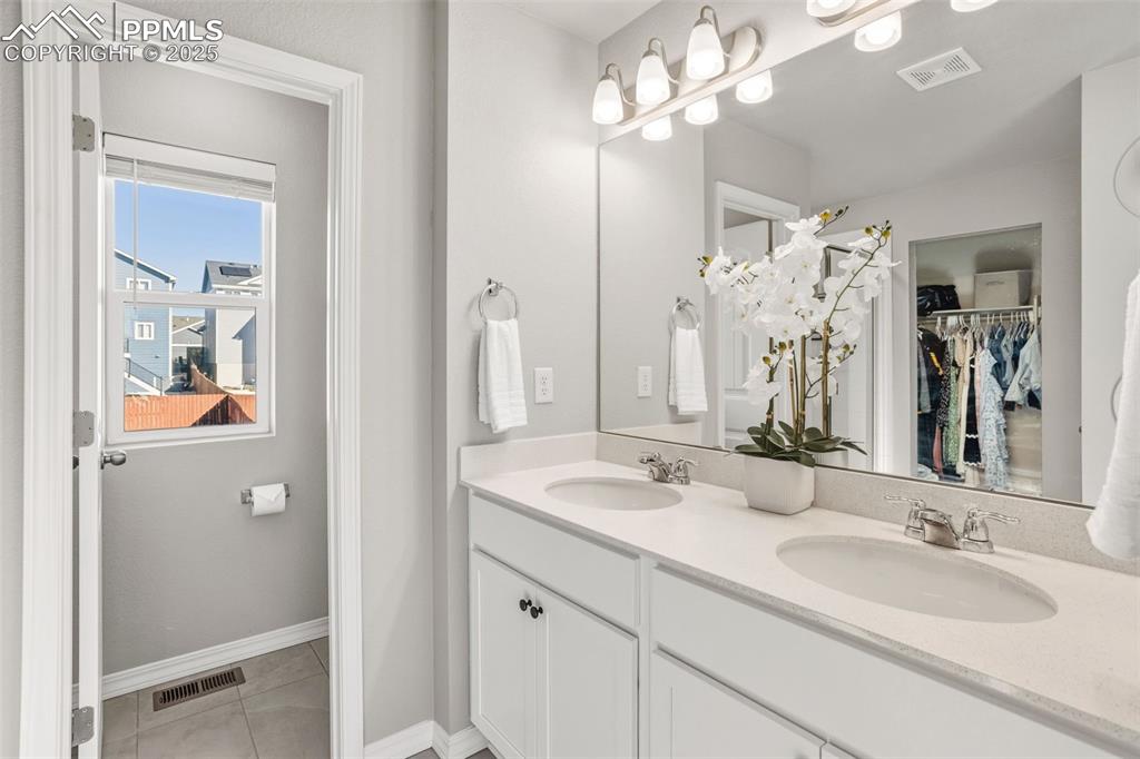 Bathroom featuring double vanity, a spacious closet, and light tile patterned floors