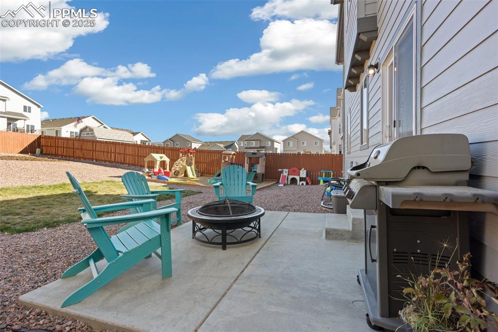 Fenced backyard with a patio, a playground, grilling area, a residential view, and a fire pit