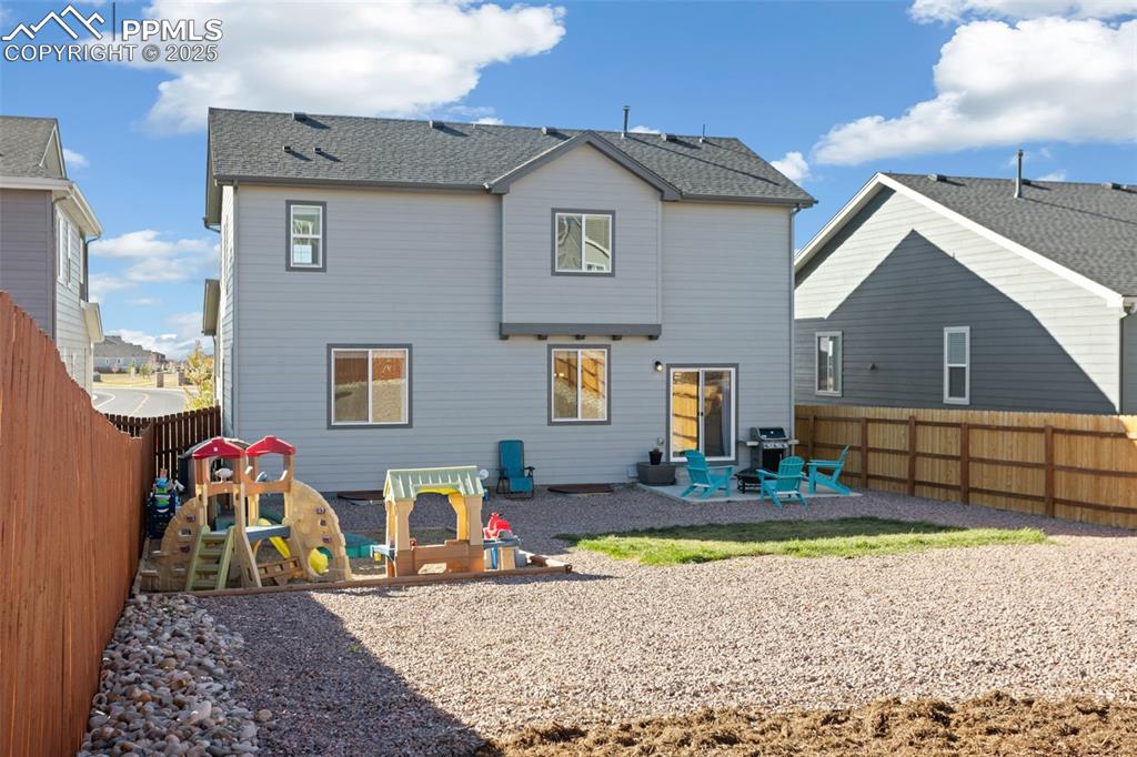 Back of property with a patio, a fenced backyard, and a shingled roof