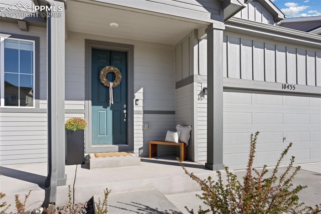 Property entrance featuring board and batten siding, a porch, and an attached garage