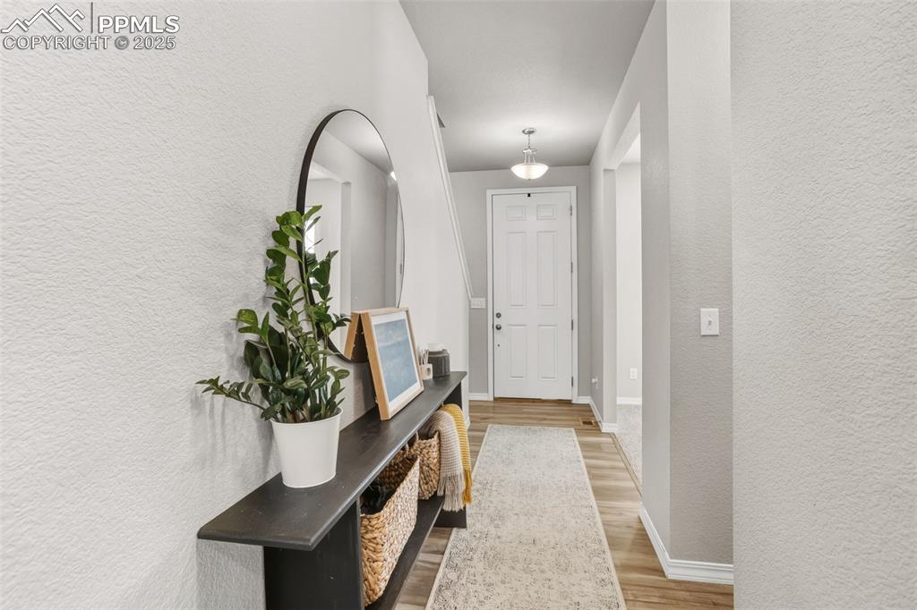 Doorway with a textured wall and wood finished floors
