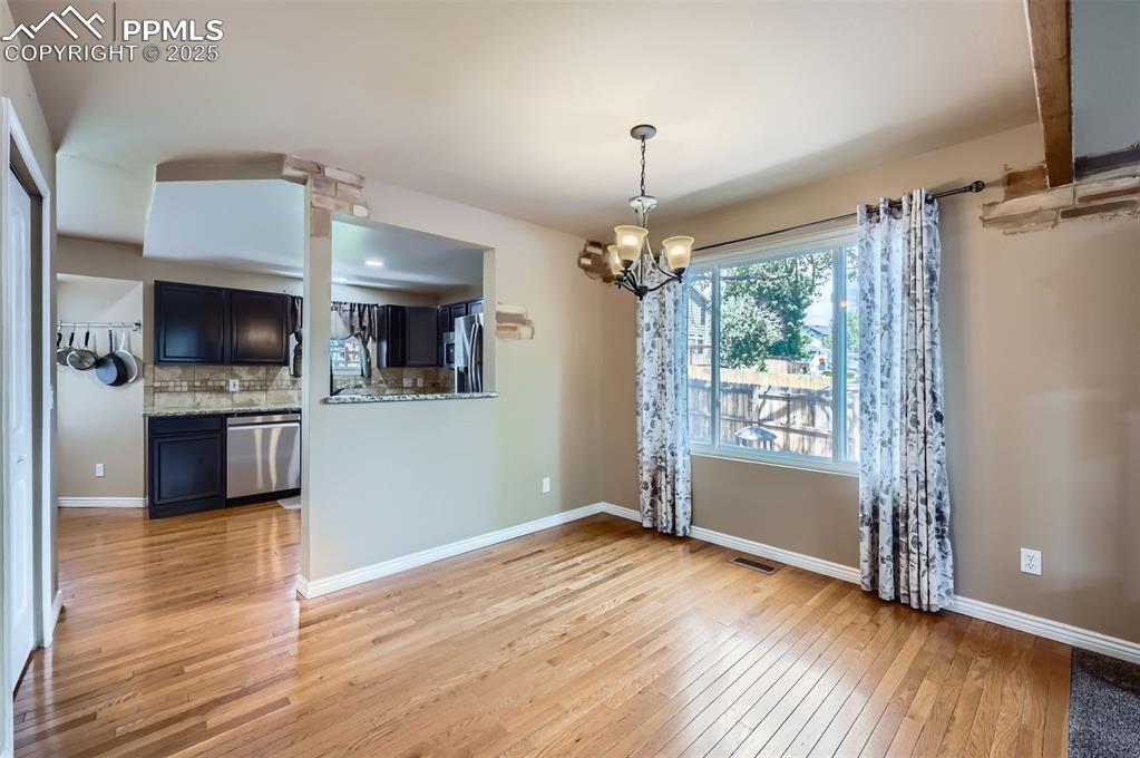 Unfurnished dining area featuring light wood finished floors and a chandelier