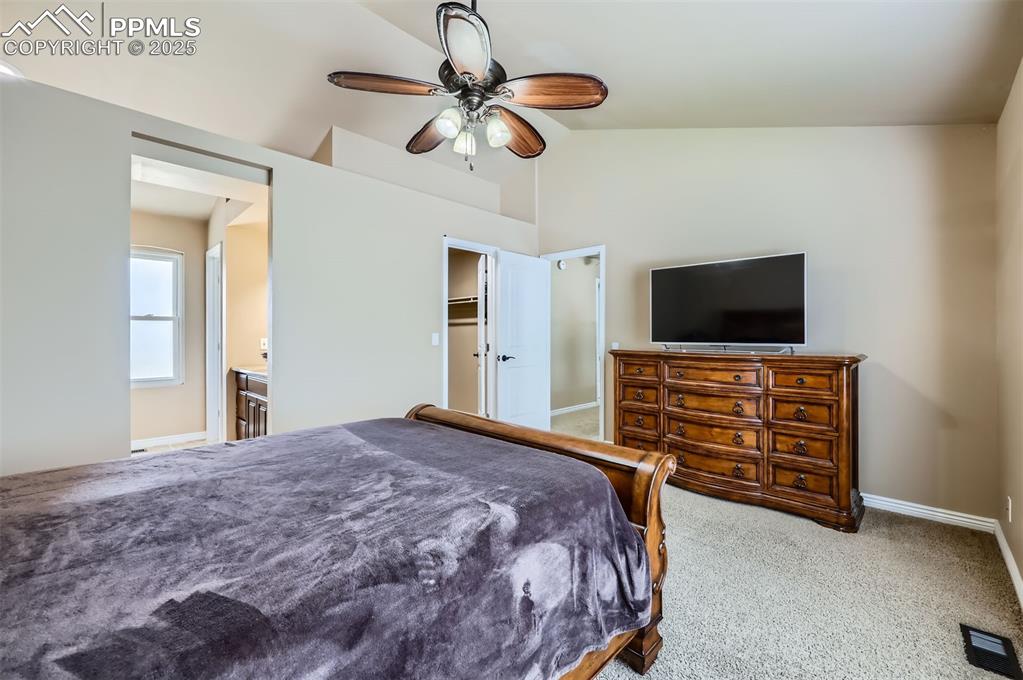 Bedroom featuring lofted ceiling, carpet flooring, ceiling fan, and ensuite bath