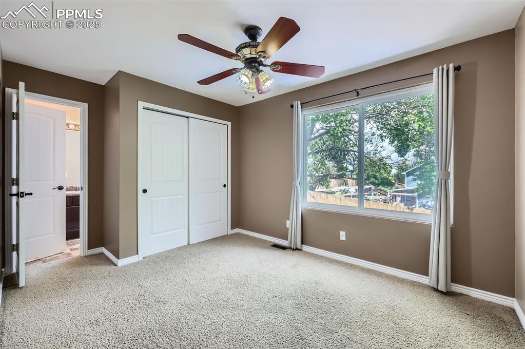 Carpeted ensuite bedroom with a closet, carpet, ceiling fan, and connected Jack and Jill bathroom