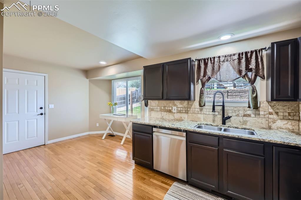 Kitchen with dishwasher, tasteful backsplash, light wood flooring, light granite counters, and recessed lighting