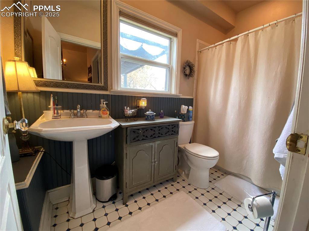 The FULL bathroom features custom tile flooring and a beautifully preserved historic cabinet, adding charm and character to this Colorado Springs home.