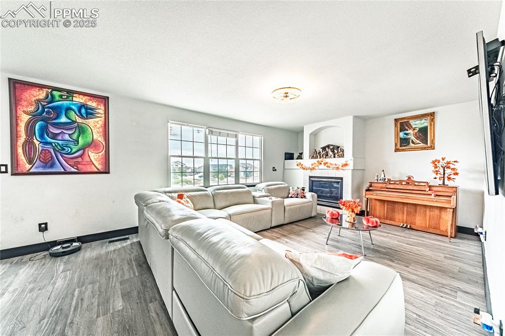 Living room with a tile fireplace, wood finished floors, and a textured ceiling