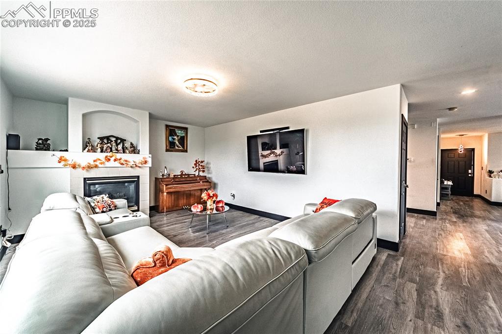 Living area featuring dark wood-type flooring, a tiled fireplace, and a textured ceiling