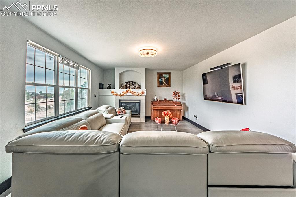 Living area featuring a tile fireplace, a textured ceiling, and wood finished floors