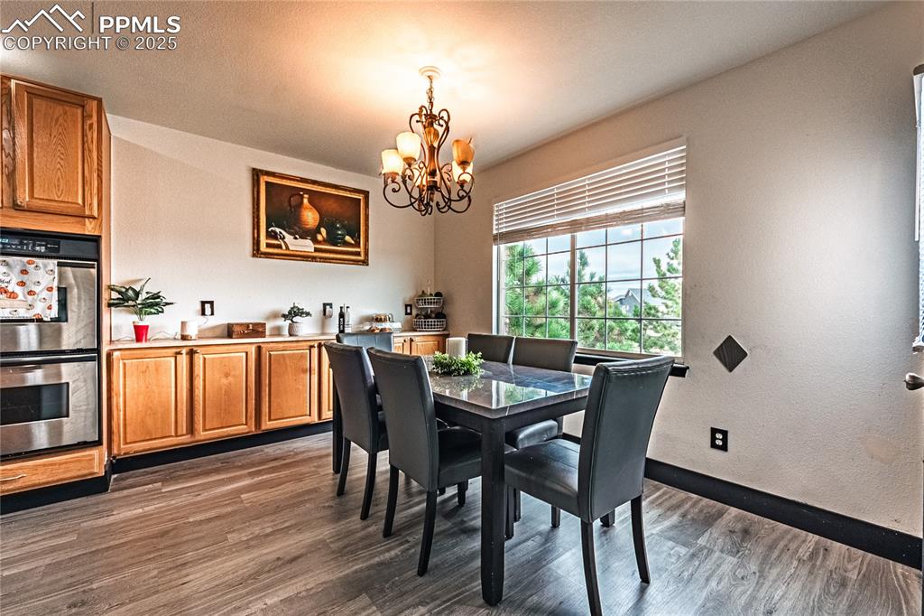 Dining room with dark wood finished floors, a chandelier, and a textured wall