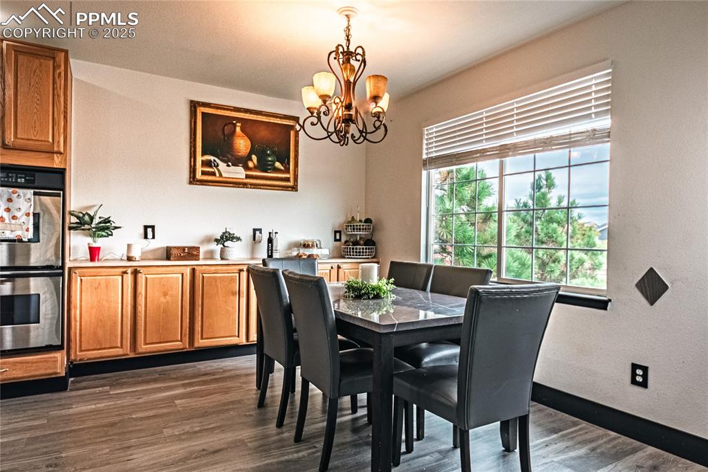 Dining area featuring dark wood finished floors, a chandelier, and a textured wall