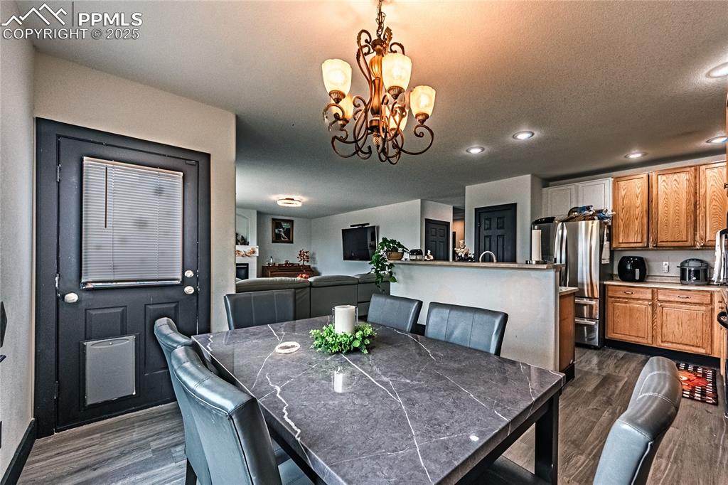 Dining space with dark wood-style floors, a chandelier, and recessed lighting