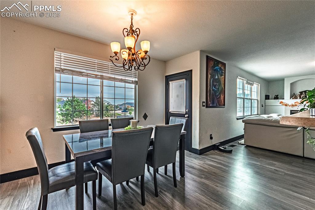 Dining area with a chandelier, a textured ceiling, dark wood-style flooring, and a textured wall