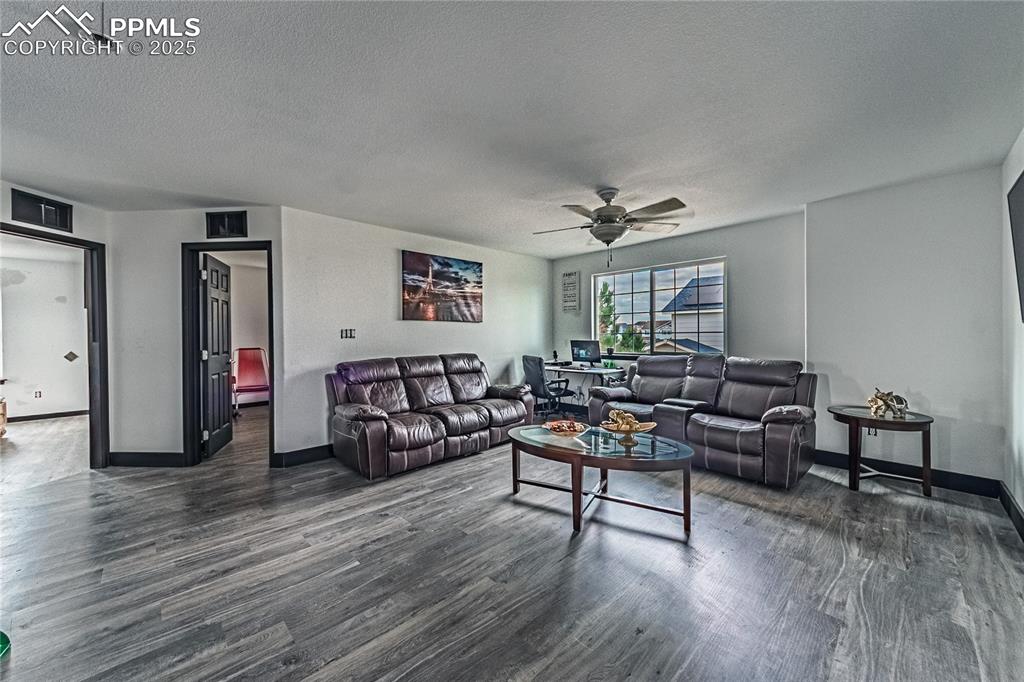 Living room with dark wood-style flooring, a textured ceiling, and a ceiling fan