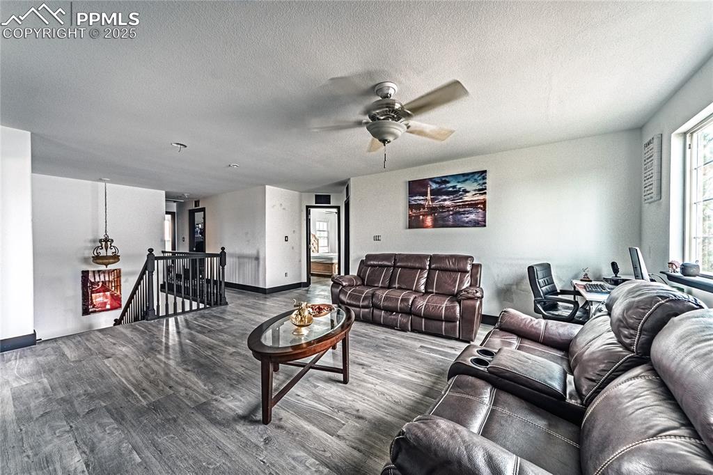 Living area featuring wood finished floors, a textured ceiling, and ceiling fan