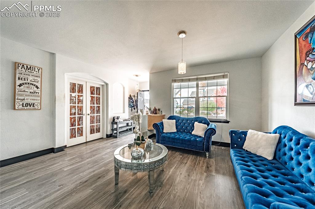 Living room featuring arched walkways, wood finished floors, a textured ceiling, and french doors
