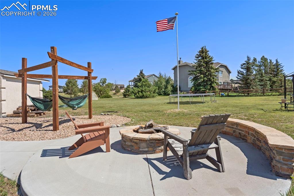 View of patio featuring a trampoline, hammock station and a fire pit