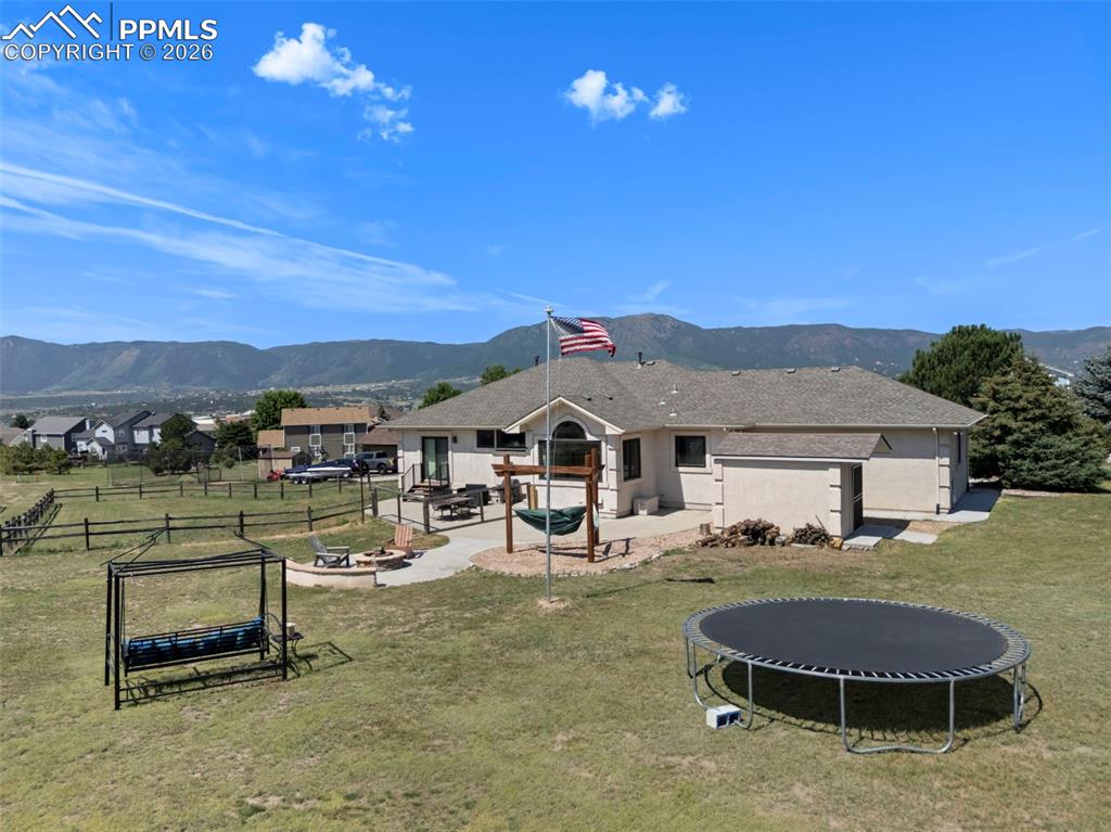 Back of property featuring a mountain view, a patio, a fire pit, and space for trampoline