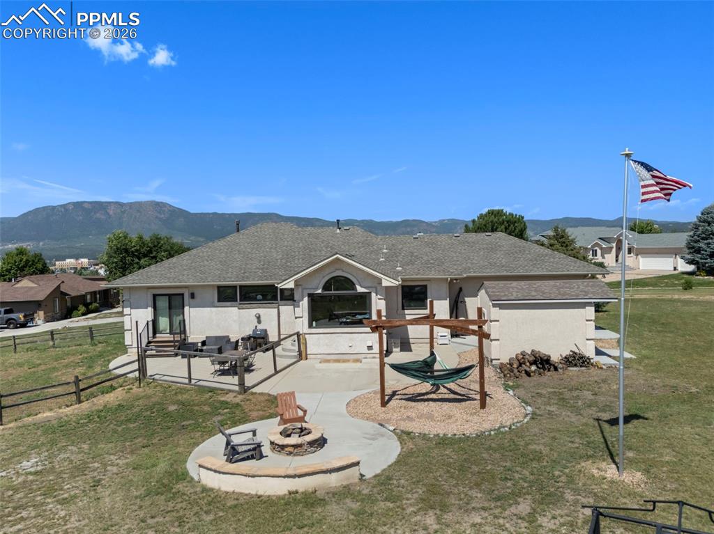 Back of property with a patio area, a fire pit, a mountain view, and roof with shingles