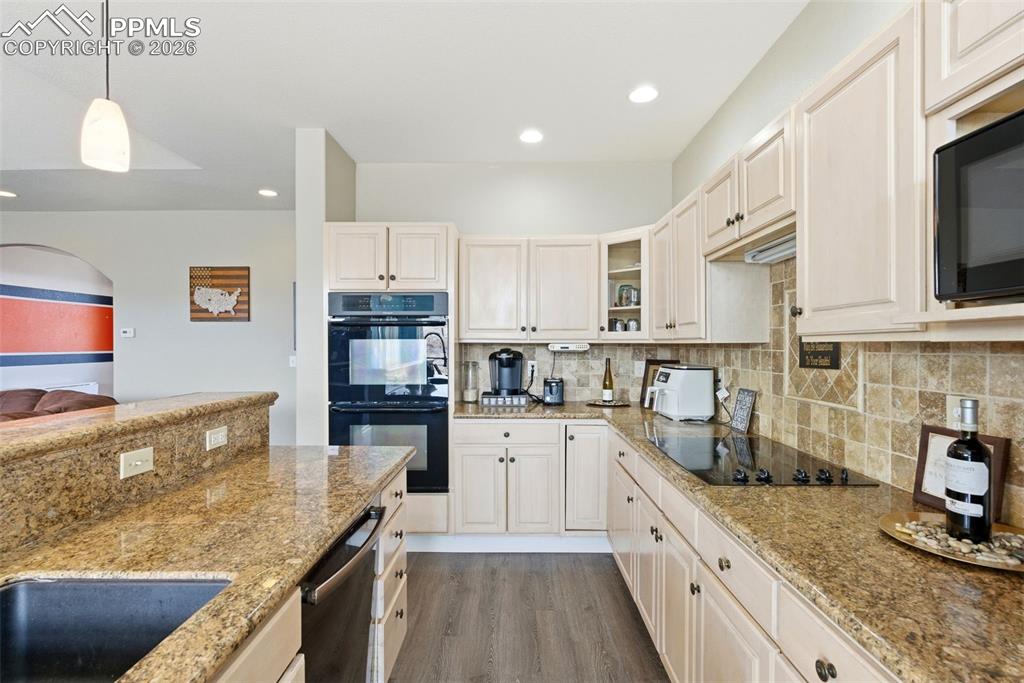 Kitchen with decorative light fixtures, light stone countertops, and grey plank floors