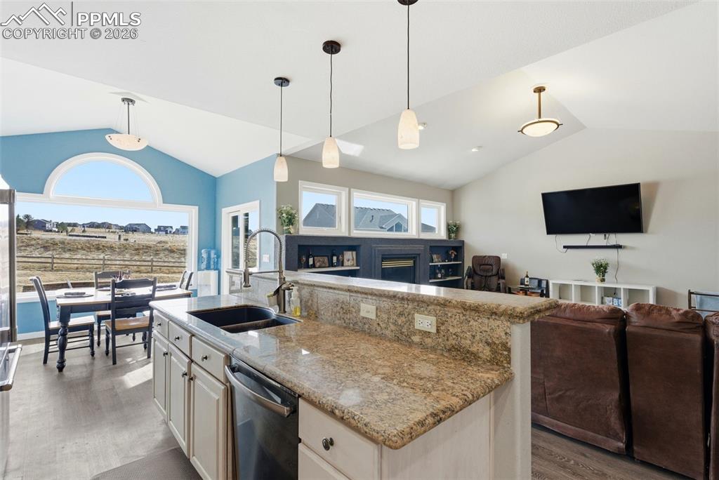 Kitchen featuring light stone counters, open floor plan, a fireplace, and all appliances included