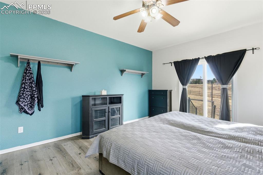Master bedroom featuring plank finished floors and ceiling fan and walk out to patio