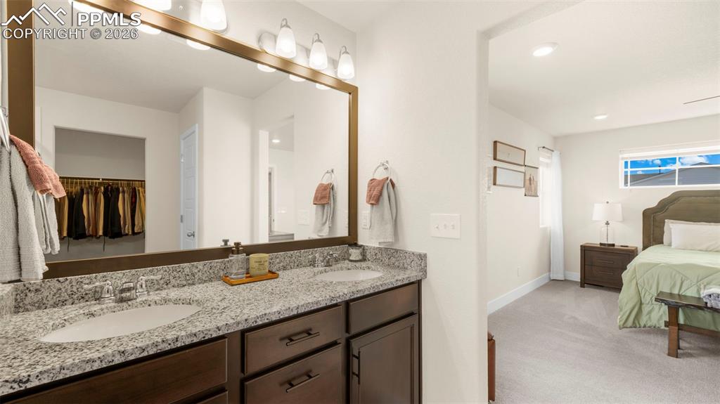 Bathroom with double vanity, light colored carpet, ensuite bathroom, recessed lighting, and a spacious closet