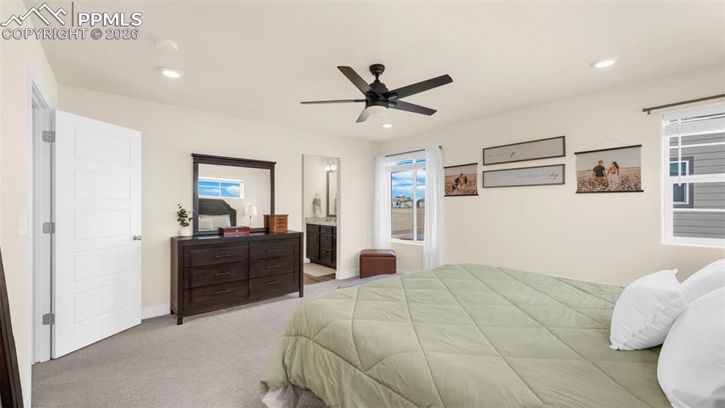 Bedroom with light carpet, ceiling fan, ensuite bath, and recessed lighting