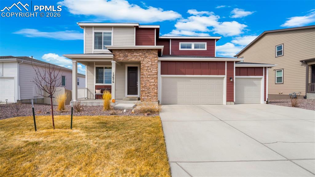 View of front of home featuring board and batten siding, covered porch, driveway, a front yard, and a garage