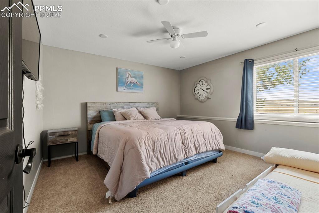Carpeted bedroom featuring ceiling fan and baseboards