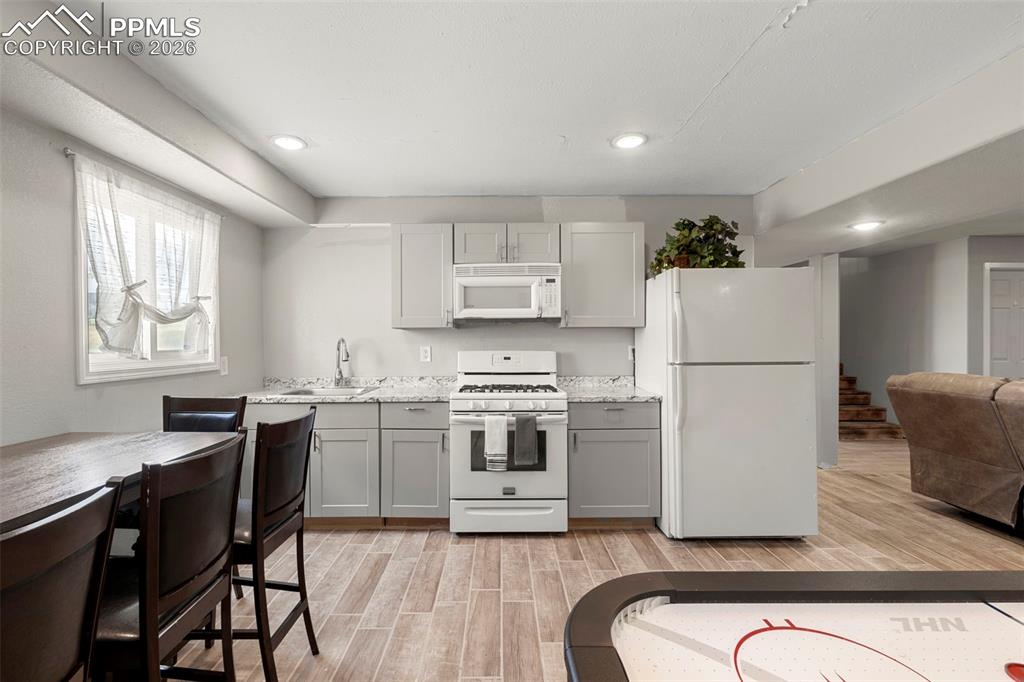 Kitchen featuring white appliances, wood tiled floors, open floor plan, recessed lighting, and gray cabinetry
