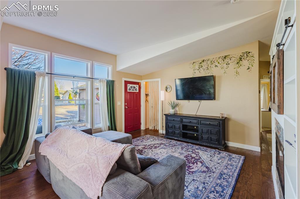 Living area with dark wood-style floors, a barn door, and vaulted ceiling