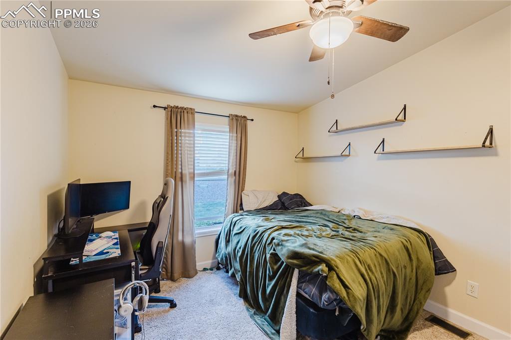 Bedroom featuring a desk, light colored carpet, and a ceiling fan