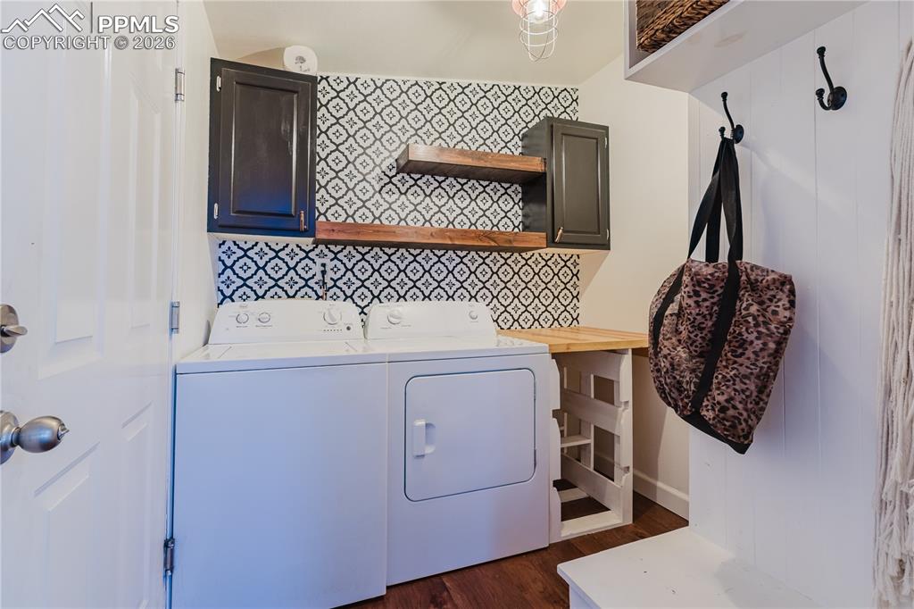 Laundry room featuring cabinet space, dark wood finished floors, and washer and clothes dryer