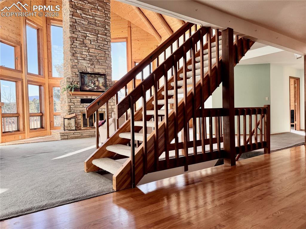Stairway featuring a high ceiling, wood finished floors, and a stone fireplace