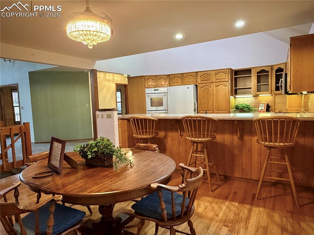 Dining area with light wood finished floors, recessed lighting, and vaulted ceiling