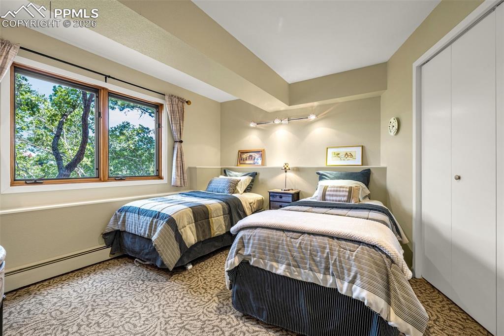 Carpeted bedroom with a baseboard radiator and a closet