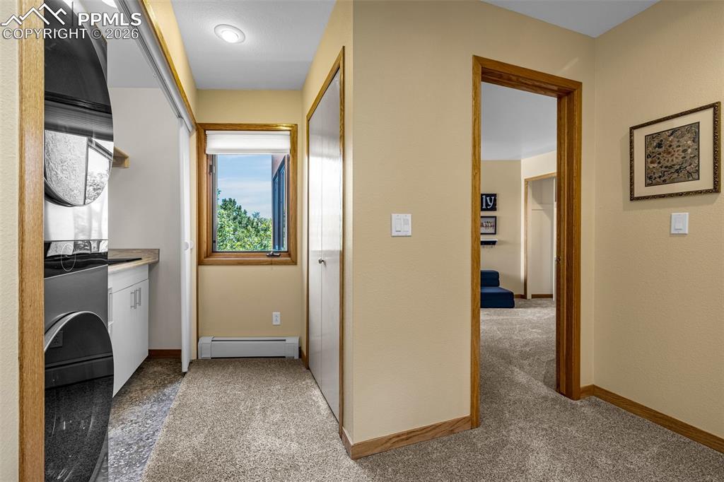 Laundry area featuring baseboard heating, washer / dryer, and light carpet
