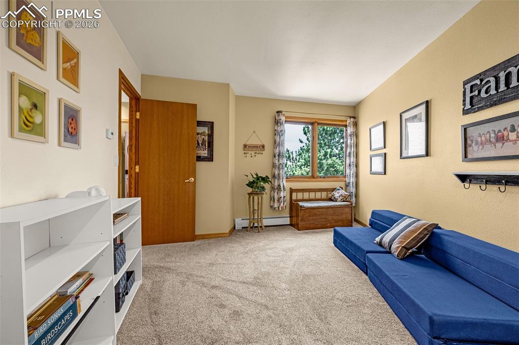 Living area featuring light colored carpet and baseboard heating